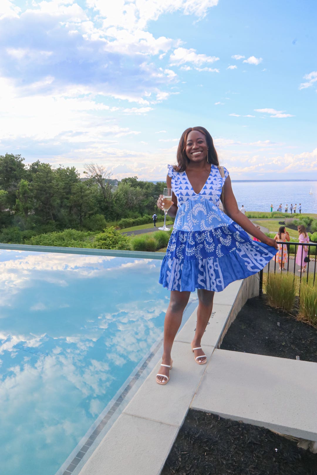 woman in blue and white dress standing in front of pool in Maine